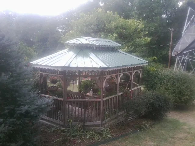 Green metal roof on a backyard gazebo surrounded by garden beds in Selma
