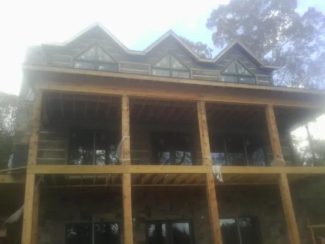 Dormers and porch framing on a large log home under construction — Roof Coating work by our crew in Selma