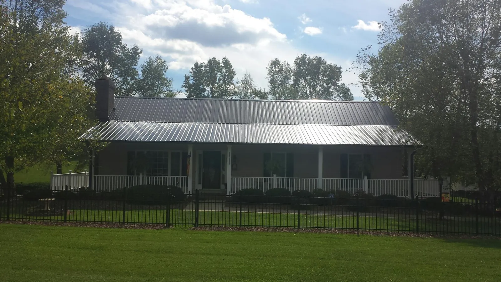 Gray metal roof on a brick ranch with a full width front porch — Gutter Guard Installation work by our crew in Selma