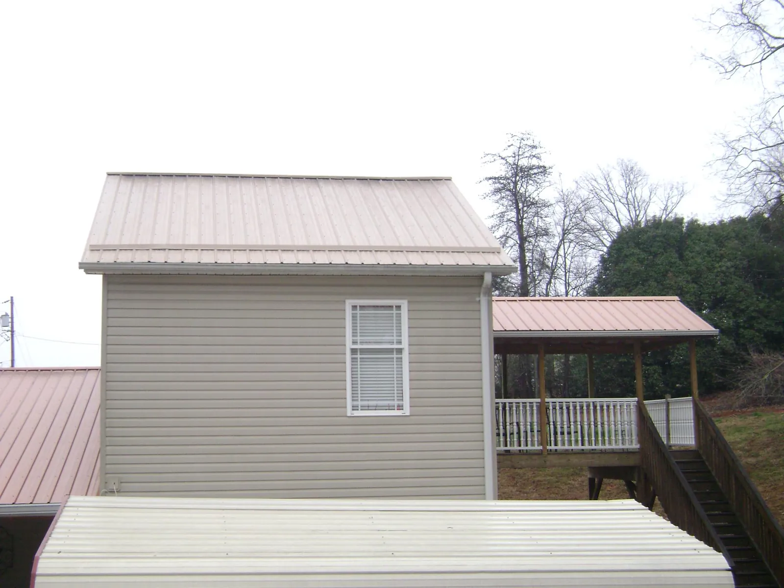 Tan metal roofs on a two story addition and attached porch, from a Roof Replacement job in Selma