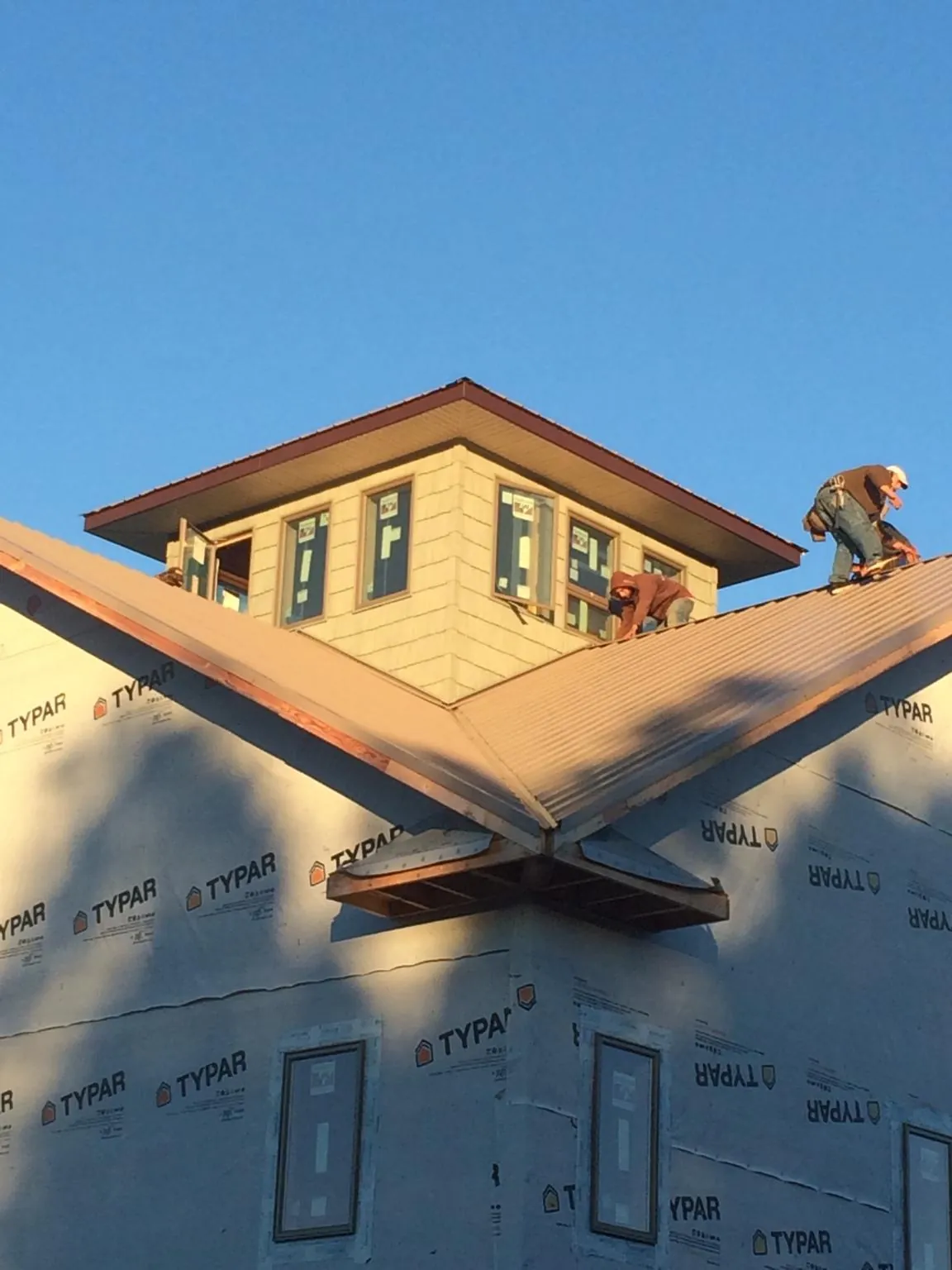 Roofers working around a rooftop cupola on a new metal roof at sunset — Roof Waterproofing in Selma by Roofing Brothers